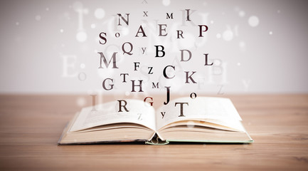 Opened book with flying letters