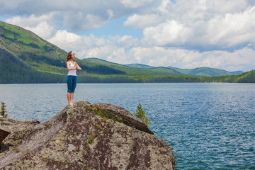 Young woman is practicing yoga at mountain lake