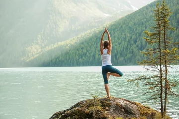 Foto auf Acrylglas Yogaschule Junge Frau praktiziert Yoga am Bergsee