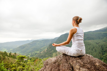 Woman is doing yoga exercises in mountains