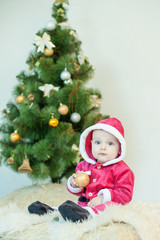 Small boy in Santa suit plays in white studio