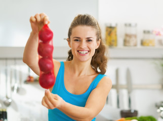 Happy young woman showing bunch of red onions