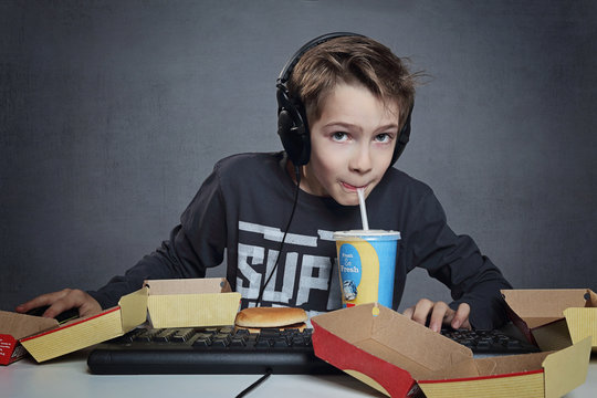 enfant jouant à l'ordinateur buvant et mangeant