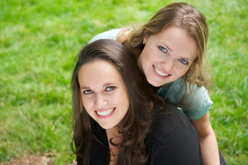 Closeup portrait of two beautiful girls smiling outdoors