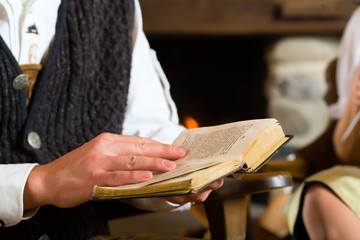Junger Mann in einer Almhütte liest Bibel