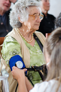 Nurse checking senior woman blood pressure