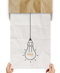 hand pulling light bulb crumpled paper out of recycle envelope