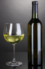 White wine glass and bottle of wine on grey background