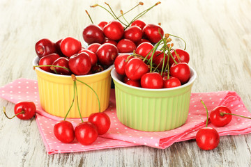 Cherry berries in bowls on wooden table close up