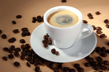 Cup of coffee with coffee beans on beige background