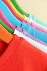 Different shirts on colorful hangers on beige background