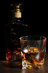Glass of whiskey with bottle, on dark background