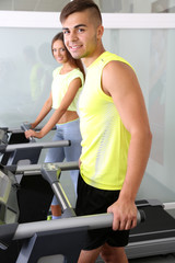 Obraz na płótnie Canvas Guy and girl on treadmills at gym
