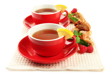 Cups of tea with cookies and raspberries isolated on white