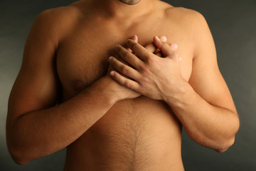 Obraz premium Young man with chest pain on grey background