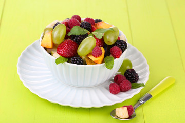 Fruit salad in bowl, on wooden background