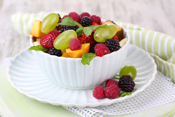 Fruit salad in bowl, on wooden background