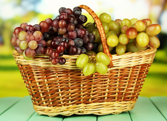 Fresh grape on wicker mat on bright background