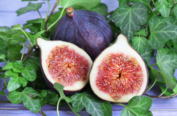 Ripe figs in leaves on wooden table close-up