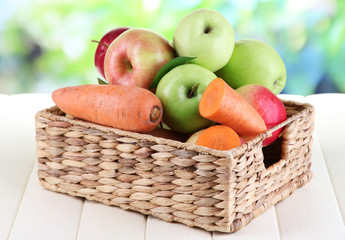 Sweet apples and carrots in basket