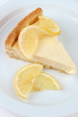Slice of  lemon cheesecake on plate, isolated on white