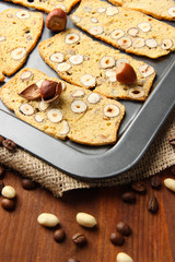 Biscotti with hazelnuts, on  dripping pan, on wooden background