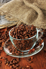 Coffee beans in cup on wooden background