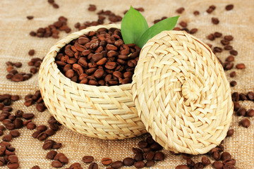 Obraz premium Coffee beans in wicker basket on table close-up