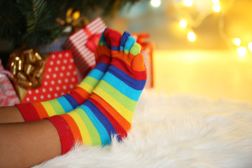 Legs in socks near Christmas tree on carped