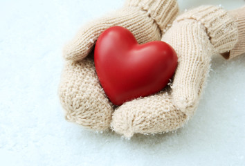 Female hands in mittens with red heart, close-up