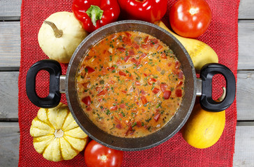 Top view on pot of tomato soup on old wooden table