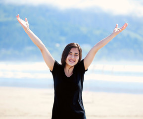 Happy young woman on beach, arms outstretched