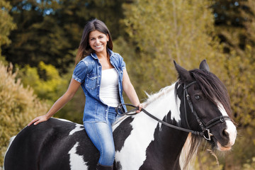 attractive brunette female rider sitting on her horse smiling
