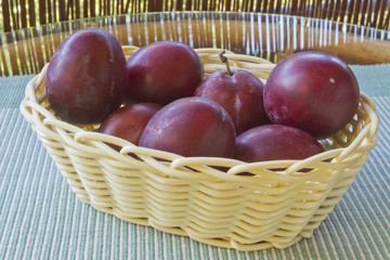 ripe plums in a basket on the table