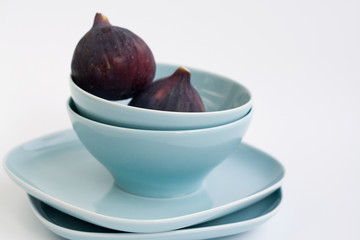 Ripe figs lying on a blue plate on a white background
