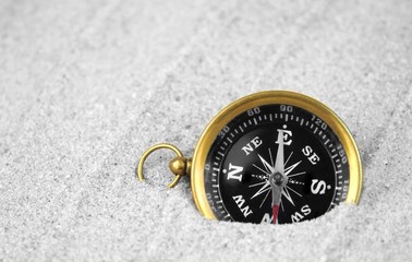 Old compass buried in sand.