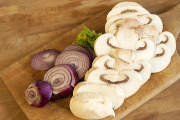 Chopped fresh raw onion and mushroom on a wooden board