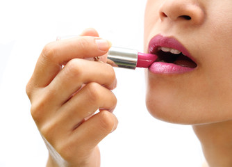 beautiful woman is applying her lips with pink lipstick on white