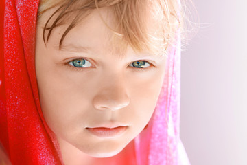 Portrait of calm blond Caucasian little girl in red shawl