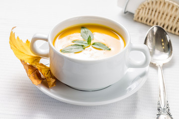 Pumpkin soup with basil on served table