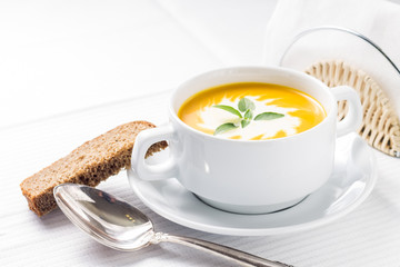 Pumpkin soup with basil on served table