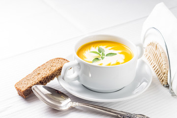 Pumpkin soup with basil on served table