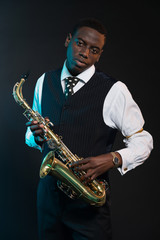 Fototapeta na wymiar Retro african american jazz musician holding his saxophone. Wear