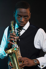 Obraz na płótnie Canvas Retro african american jazz musician holding his saxophone. Wear