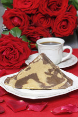 Piece of halvah on white plate. Rose petals around, bouquet of r