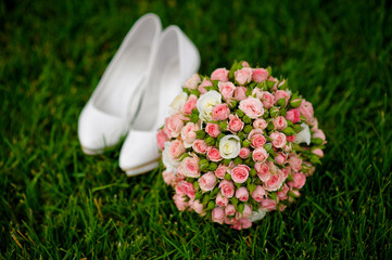 bridal bouquet and white female shoes on grass