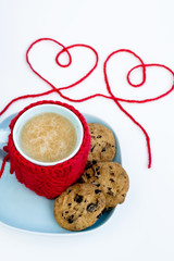 Blue cup with red knitted cover and two hearts from threads