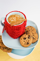 Blue cup with red knitted cover and cookies with chocolate