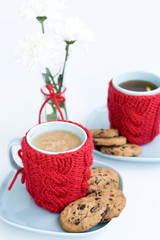 wo blue cups in knitted covers and chocolate cookies