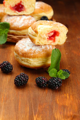 Tasty donuts with berries on wooden table